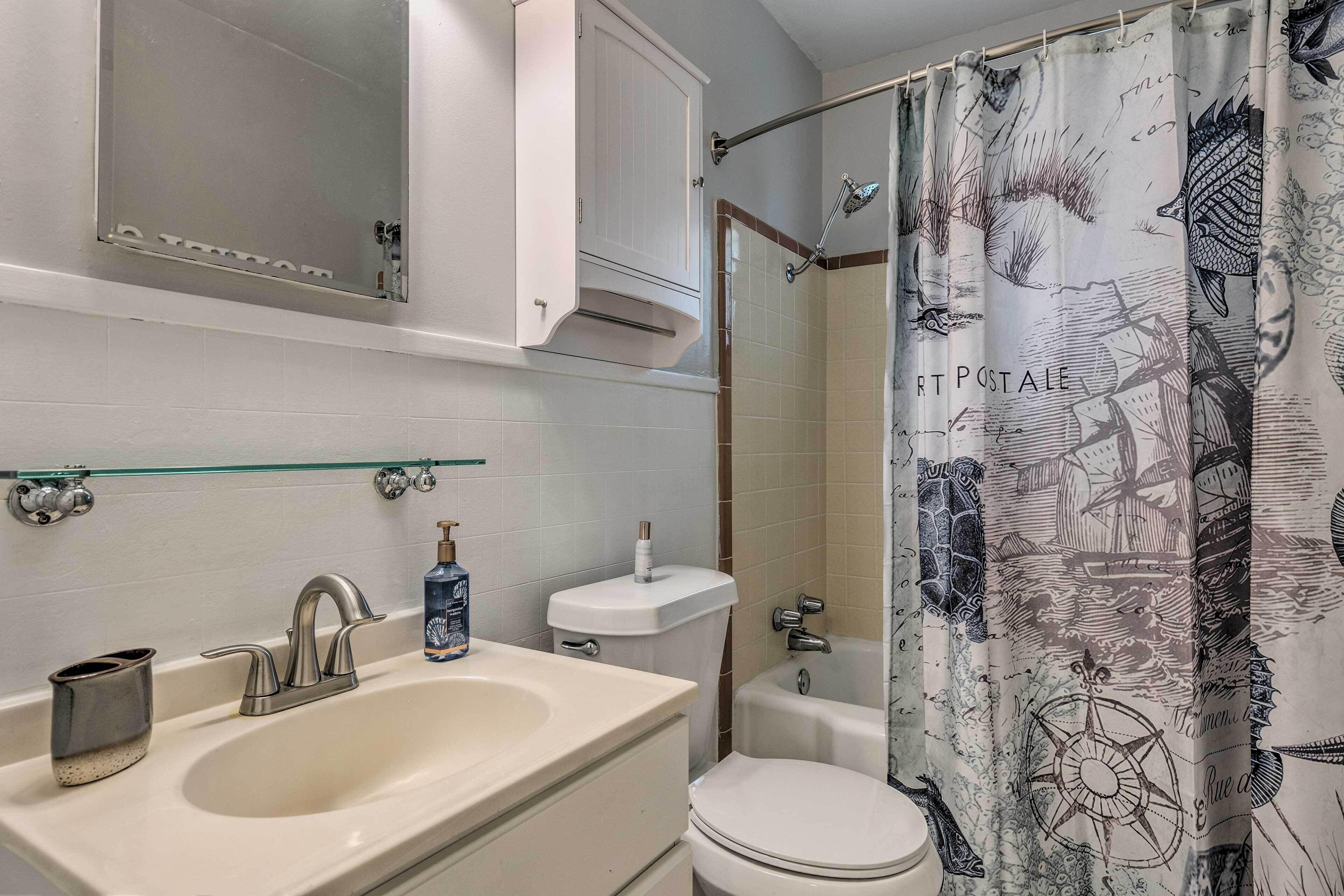 A bathroom with a sink, mirror, toilet, and shower curtain.