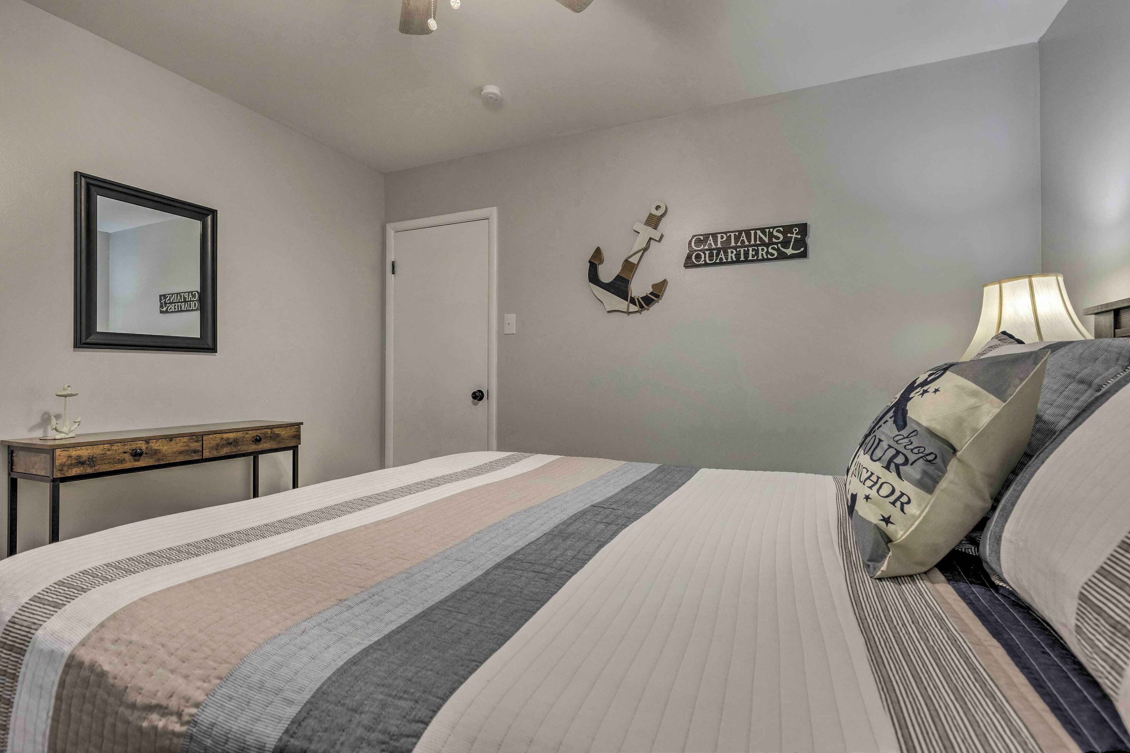 A bedroom with a bed, a nightstand, a mirror, and wall decorations.