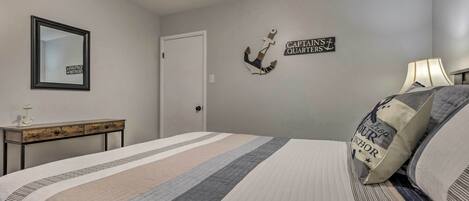 A bedroom with a bed, a nightstand, a mirror, and wall decorations.