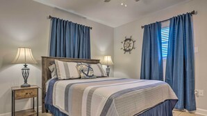 Un dormitorio con cama, dos mesitas de noche con lámparas, una alfombra y cortinas.
