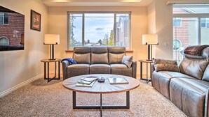 A living room with a leather sofa, a round coffee table, and two floor lamps. - Sleek Escape w/ Balcony < 1 Mi to 5th Avenue! (Anchorage)