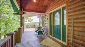 A wooden porch with a green door, two chairs, and a small table. - Cabin Near Grand Lake' w/ Private Deck! (Fairland)