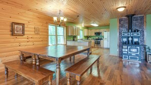 A spacious kitchen with wooden cabinetry, a large wooden dining table, and a built-in wood stove. - Cabin Near Grand Lake' w/ Private Deck! (Fairland)