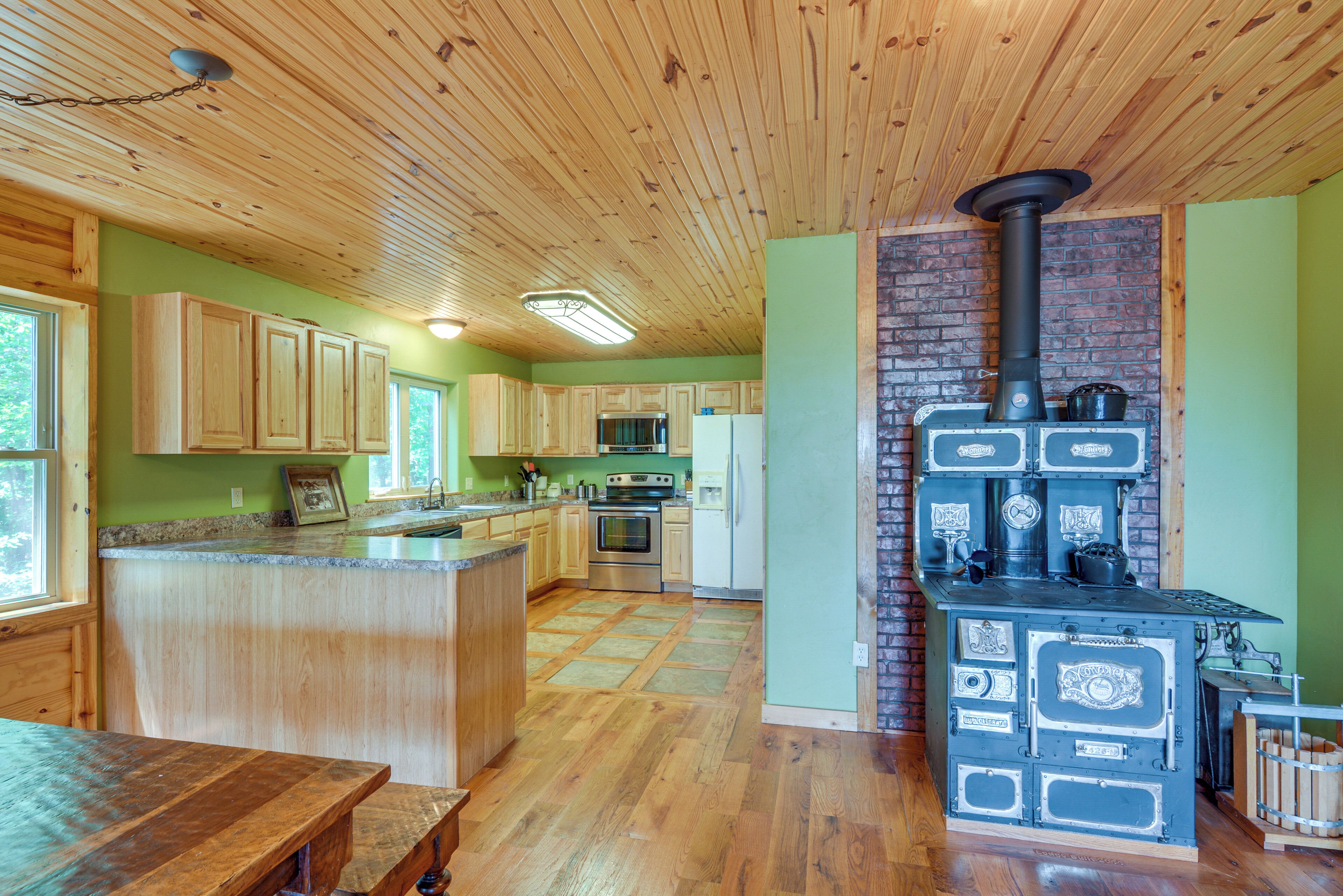 A kitchen with wooden cabinets, a central island, a stove, and a brick wall.