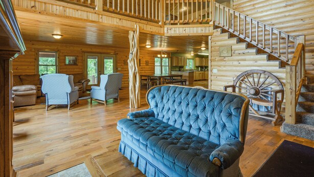 A spacious living area with a blue sofa, wooden flooring, a wooden staircase, and a ceiling fan. - Cabin Near Grand Lake' w/ Private Deck! (Fairland)