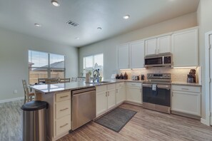 A modern kitchen with white cabinets, stainless steel appliances, and a large island. - Wolfforth Home w/ Yard ~ 14 Mi to Lubbock (Wolfforth)