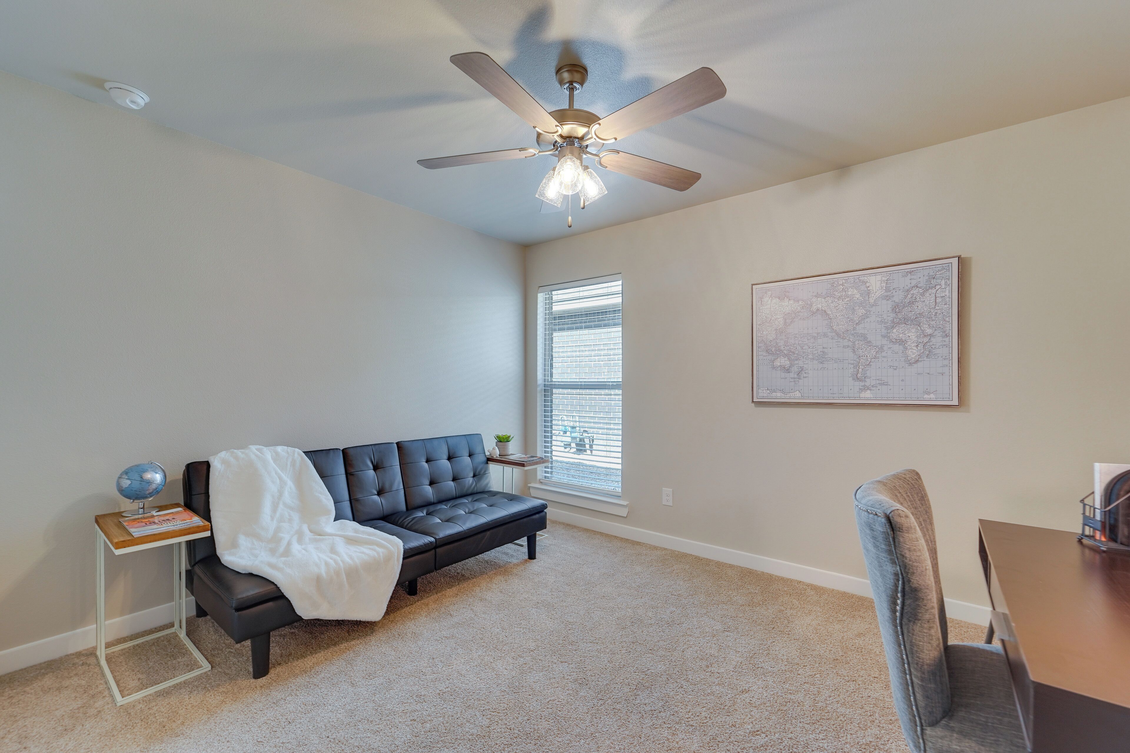 A room with a ceiling fan, a sofa, a dining table, and a window with blinds.