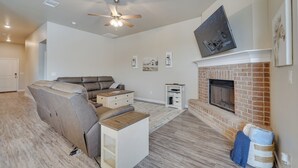 Ein Wohnzimmer mit Ecksofa, Kamin, Deckenventilator und flachbildschirm, der über dem Kamin montiert ist.
