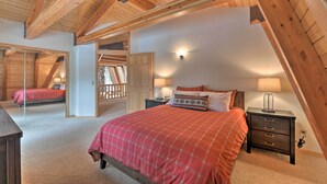 A bedroom with a sloped ceiling, a bed with a red plaid bedspread, a nightstand with a lamp, and a wooden wardrobe. - 'wild Huckleberry Cabin' in Alpine: Fire Pit, Deck (Alpine)