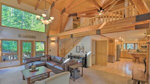 A spacious living area with a large window, a wooden staircase, and a kitchen area. - 'wild Huckleberry Cabin' in Alpine: Fire Pit, Deck (Alpine)