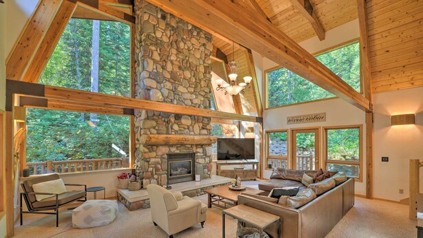 A spacious living area with a stone fireplace, large windows, and a cozy seating arrangement. - 'wild Huckleberry Cabin' in Alpine: Fire Pit, Deck (Alpine)