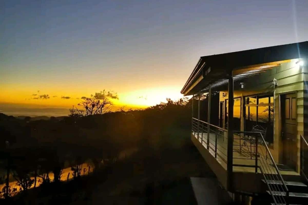 A modern building with a balcony overlooking a sunset.