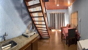 Une cuisine compacte comprenant un évier, une cuisinière et une petite table recouverte d’une nappe à carreaux.