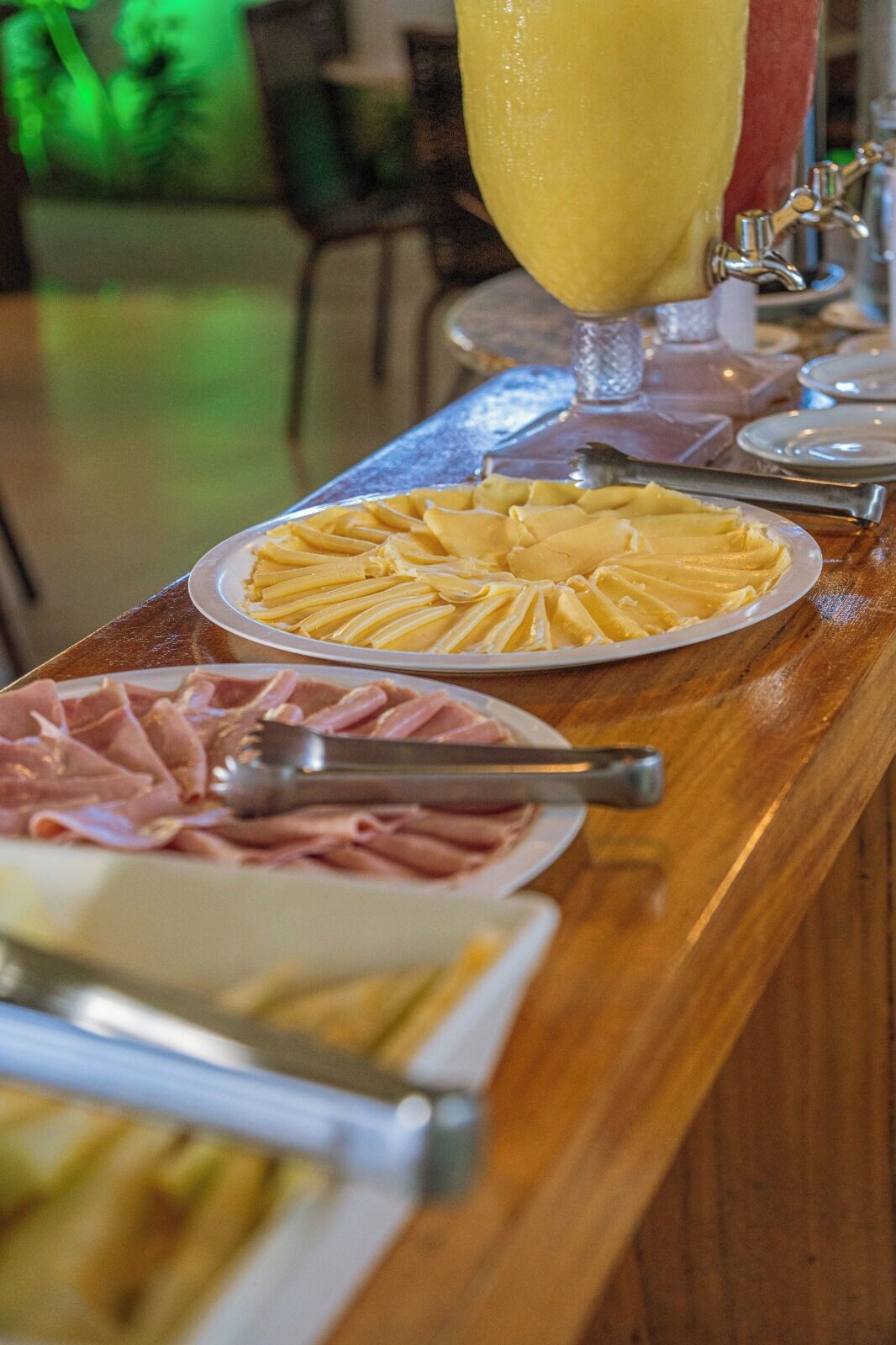 Un buffet proposant divers plats, notamment des pâtes, du jambon et une boisson jaune.