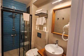 A modern bathroom with a glass-enclosed shower, a white sink, and a mirror. - Sisu Bozcaada (Bozcaada)