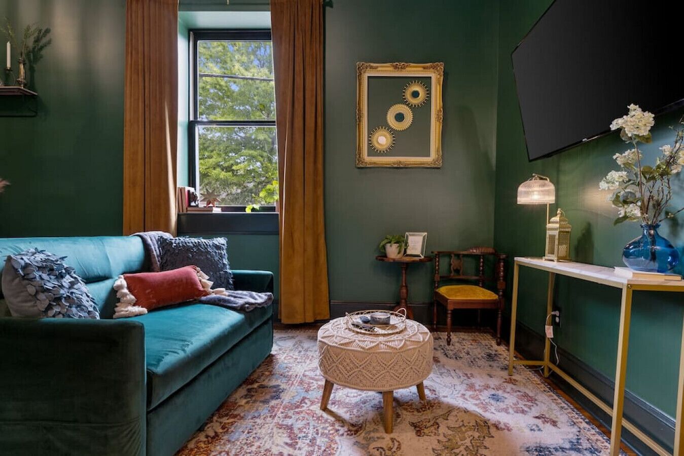Un salon chaleureux avec un canapé de couleur turquoise, une petite table ronde et un téléviseur fixé au mur.