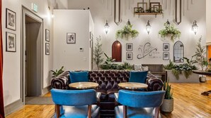 A modern lounge area with a leather sofa, two blue chairs, and a small round table. - Sherlock + Watson @ The Vestry on Read (Columbia)