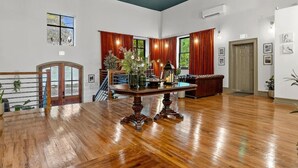 A spacious room with a wooden floor, a dining table with chairs, a sofa, and a staircase. - Sherlock + Watson @ The Vestry on Read (Columbia)