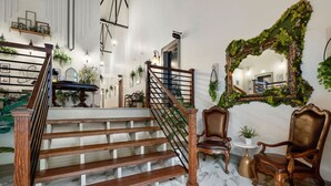A staircase with wooden steps and a metal railing, flanked by two ornate chairs and a small table. - Sherlock + Watson @ The Vestry on Read (Columbia)