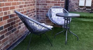 Relax in an outdoor seating area with two comfortable chairs and a round table.