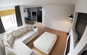 Relax in this stylish living room with a comfortable sofa, flat-screen TV, and dining area.