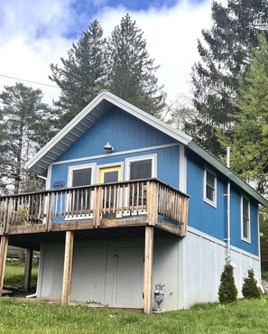 A two-story house with a balcony, a garage, and a small porch. - Mountain Koru - Tiny House in Thomas WV (Thomas)