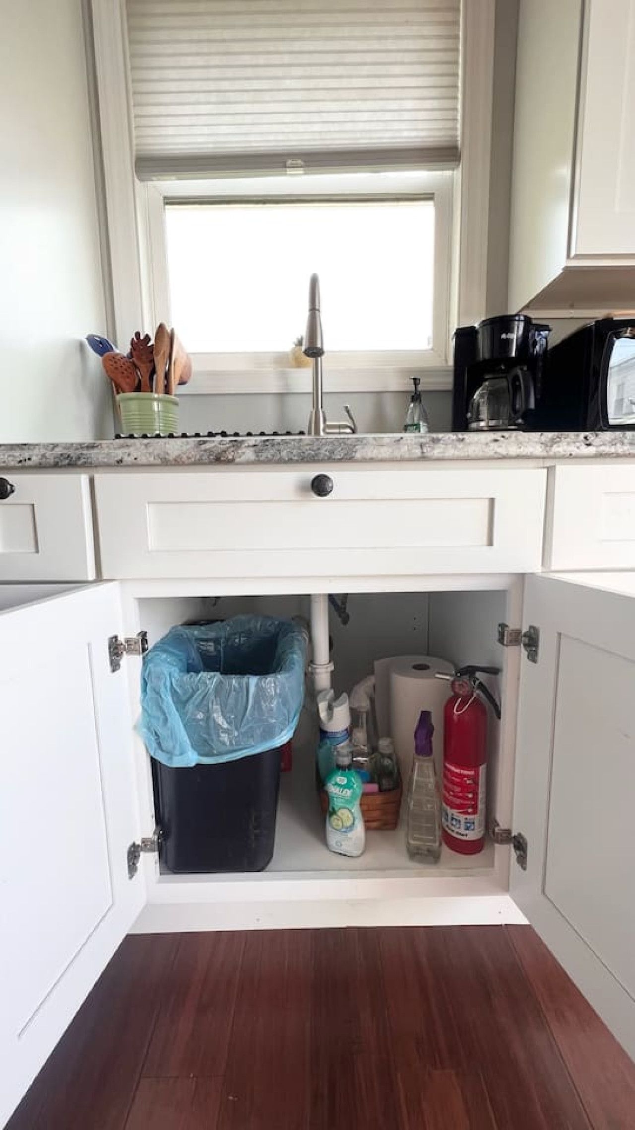 A kitchen with a window above the sink, a coffee maker, and a fire extinguisher.