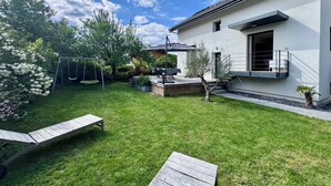A modern house with a well-maintained lawn, a swing set, and a patio area. - Maison au Calme et en Ville (Annecy)