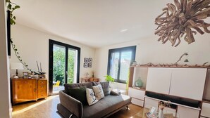 A modern living room with a grey sofa, wooden cabinet, and a glass coffee table. - Maison au Calme et en Ville (Annecy)