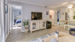 A modern living room with a TV, a dining area, and a kitchen.