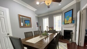 Un comedor con una mesa de madera, sillas, chimenea y un espejo grande en la pared.
