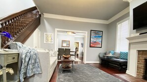 Una sala de estar con una escalera, chimenea y comedor.