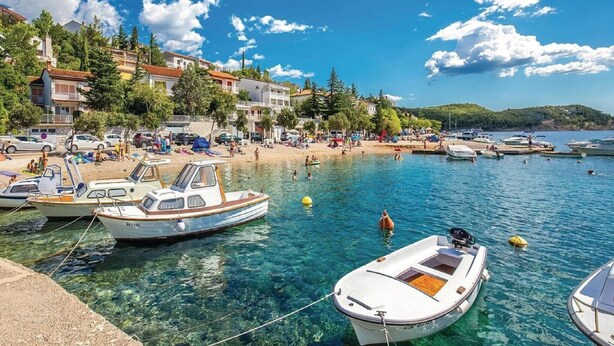 A coastal town with clear waters, boats docked, and buildings along the shore.