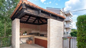 An outdoor kitchen with a tiled roof, stone walls, and a brick counter.