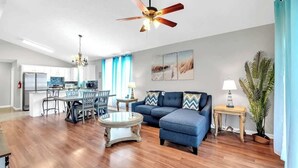 A spacious living area with a dining table, sofa, and ceiling fan. - SEASHORE · *Summer’s Special | King Bed| Cvrd Back Porch* (Panama City Beach)