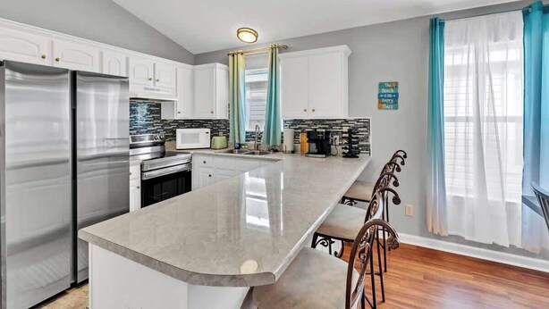 A modern kitchen with a central island, stainless steel appliances, and a view of the living area. - SEASHORE · *Summer’s Special | King Bed| Cvrd Back Porch* (Panama City Beach)