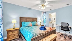 A bedroom with a bed, bedside tables, a desk, a chair, a ceiling fan, and a window with curtains. - SEASHORE · *Summer’s Special | King Bed| Cvrd Back Porch* (Panama City Beach)
