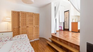 A bedroom with a bed, wooden wardrobe, and a bathroom visible through a doorway. - Apartments Ilija Njavro - Studio Apartment (Jadranovo)
