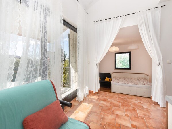 A room with a large window, a bed, a sofa, and a chair.
