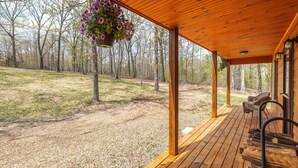 A wooden deck with a hanging flower pot, a bench, and a chair. - Secluded Getaway with Private Meramec River Access and Floating (Steelville)