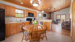 A spacious kitchen with wooden cabinets, a central island, and a dining area with wooden chairs. - Secluded Getaway with Private Meramec River Access and Floating (Steelville)