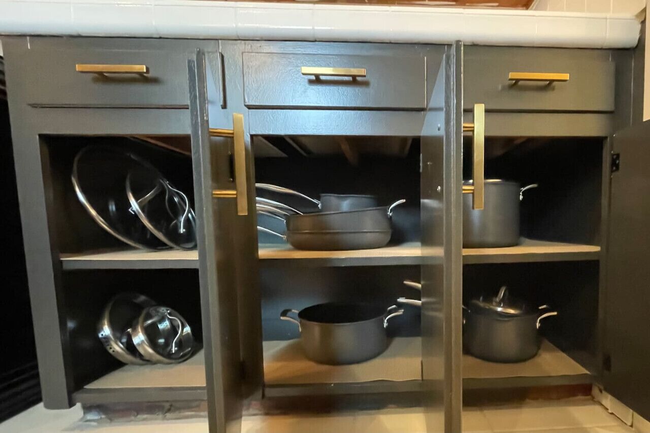 Une cuisine avec des placards ouverts où sont exposés les ustensiles de cuisine.