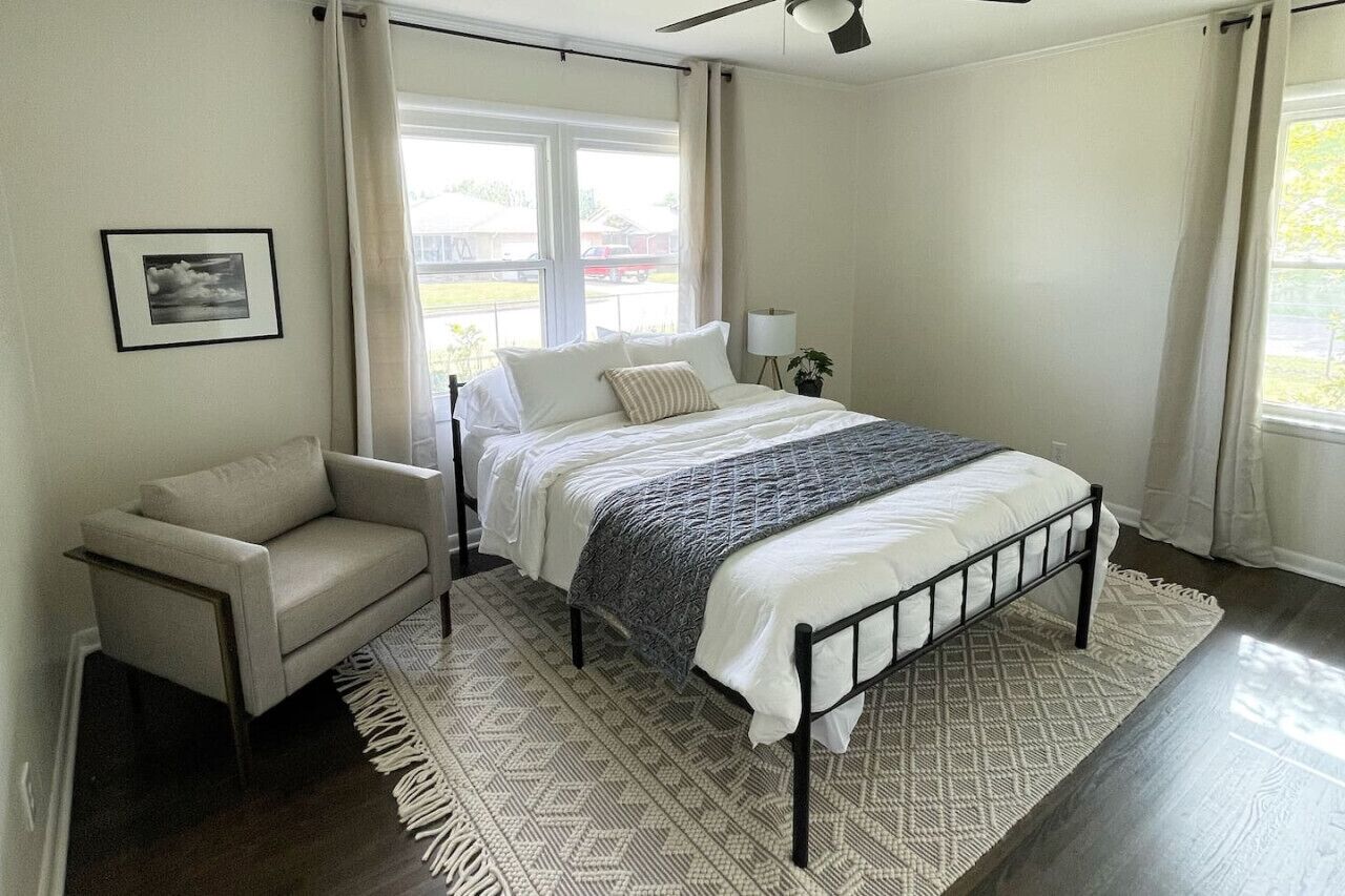 A bedroom with a bed, a chair, a window, and a ceiling fan.
