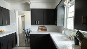 Une cuisine moderne avec des meubles de couleur sombre, des plans de travail blancs et un îlot central.