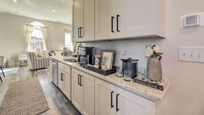 A modern kitchen with light-colored cabinets, a marble countertop, and a built-in coffee maker. - The Beaufort Flat Near Downtown & Waterfront! (Beaufort)