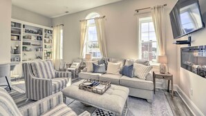 A living room with a sofa, armchairs, a coffee table, and a TV mounted on the wall. - The Beaufort Flat Near Downtown & Waterfront! (Beaufort)