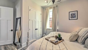 A bedroom with a bed, bedside table, and a window with curtains. - The Beaufort Flat Near Downtown & Waterfront! (Beaufort)