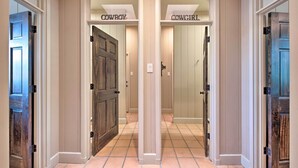 A hallway with two doors labeled "COWBOY" and "COWGIRL". - Lakefront Wallis Ranch w/ Private Beach & Patio! (Wallis)