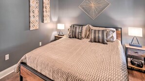 A bedroom with a large bed, two bedside tables, a wall-mounted lamp, and two wall art pieces. - Bristol Escape w/ Patio, 2 Mi to Downtown! (Bristol)