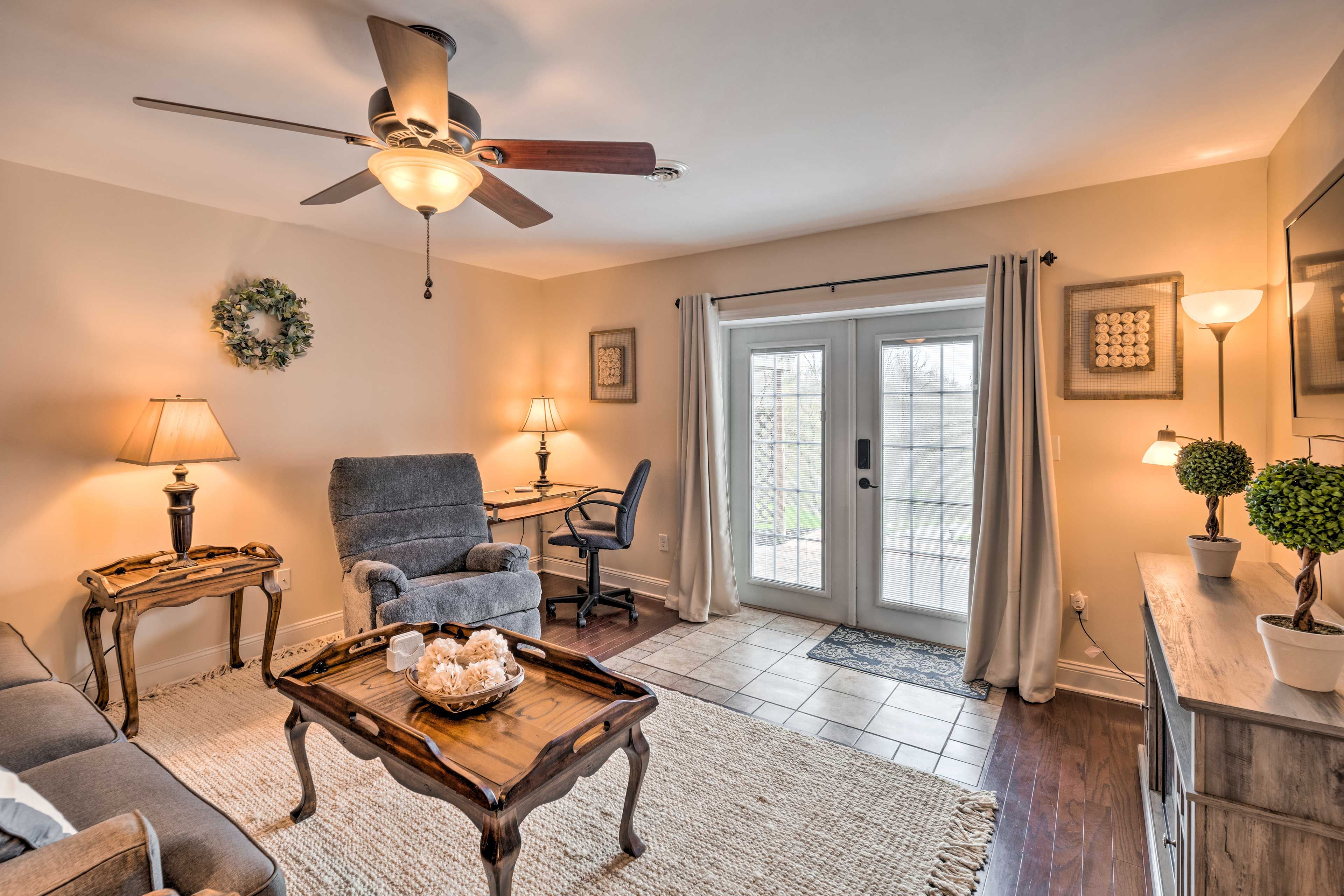 A living room with a ceiling fan, a grey armchair, a wooden coffee table, and a dining area with a table and chairs.